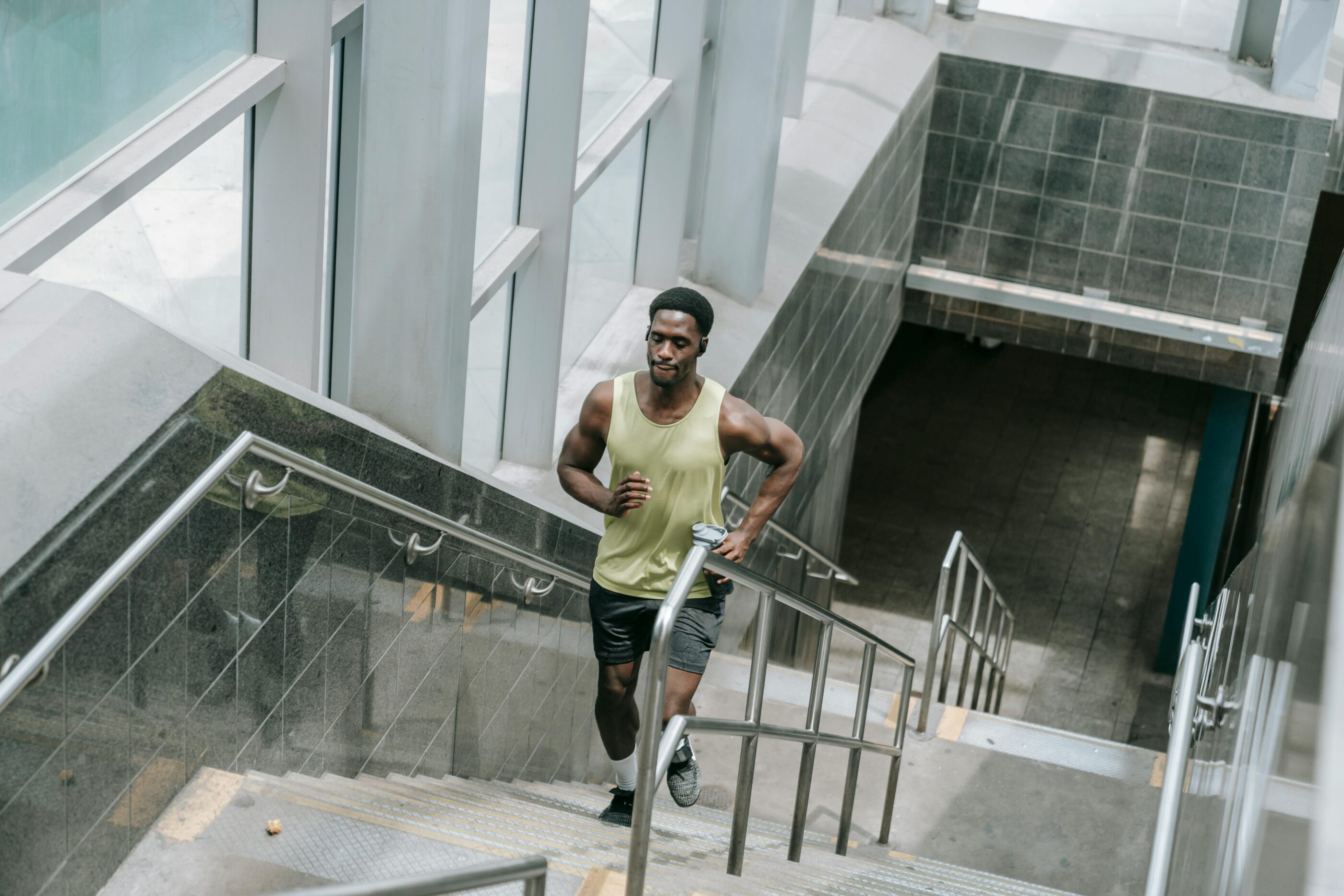 Muscular man in activewear running upstairs inside a modern building. Fitness concept.